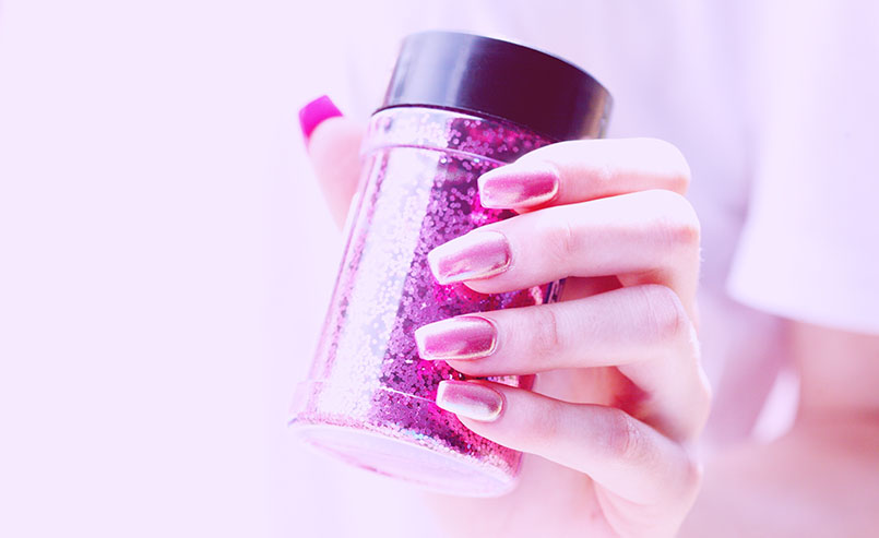 Mãos femininas esmaltadas segurando pote de glitter - destaque do post como usar brilho